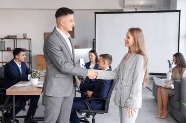 İş ortakları konferans odasında el sıkışıyor.