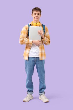 Sırt çantası ve dizüstü bilgisayarı olan genç bir çocuk.