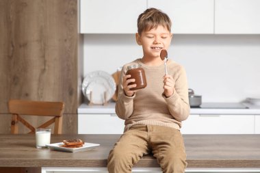 Mutfaktaki masada oturan bir kavanoz çikolatalı tatlı çocuk.