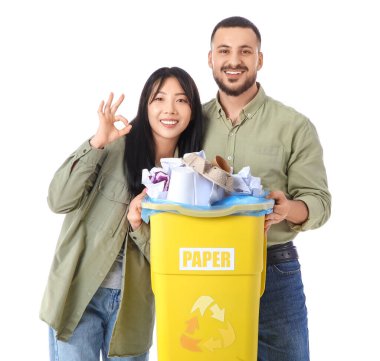 Çöp tenekesinde çöp toplayan genç bir çift beyaz arka planda sorun olmadığını gösteriyor. Küresel Geri Dönüşüm Günü