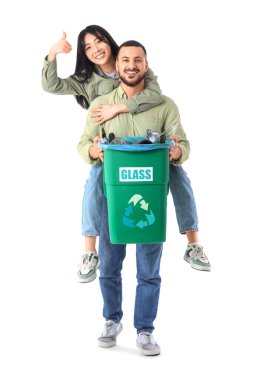 Çöp kutusunda çöpleri ayıran genç bir çift beyaz arka planda baş parmağını kaldırıyor. Küresel Geri Dönüşüm Günü