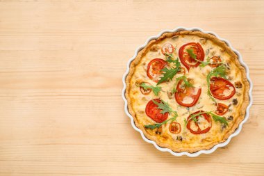 Ahşap arka planda roka yapraklı lezzetli domates tartı.