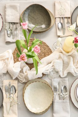 Lokantada güzel lale çiçekleri, mumlar ve temiz tabaklar olan şık bir masa.