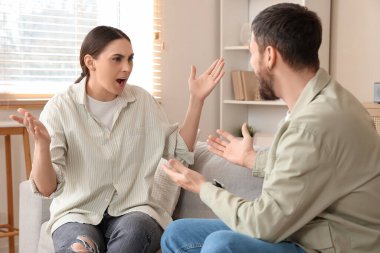 Kızgın genç çift evdeki kanepede tartışıyor.