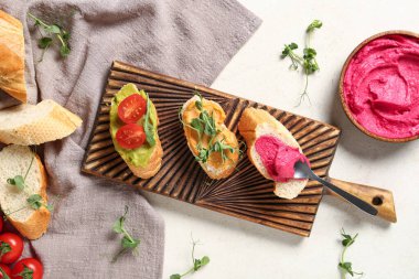 Lezzetli sandviçli kompozisyon, humus ve hafif arka planda taze lahanalar.