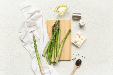 Taze yeşil kuşkonmazlı ahşap tahta tahta ve beyaz arka planda mozzarella peyniri.