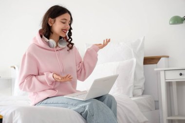 Yatak odasında dizüstü bilgisayarla çalışan Hintli kız öğrenci.