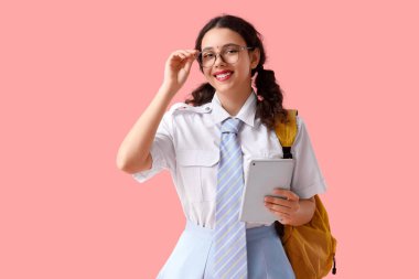 Gözlüklü, pembe arka planda tablet bilgisayarı olan Hintli bir kız öğrenci.