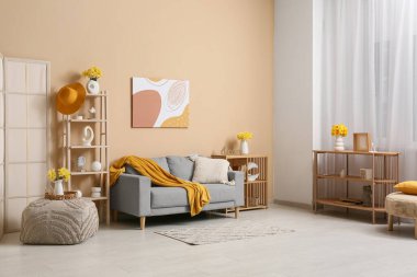 Oturma odasının içinde kanepeler, raflar ve vazolarda güzel nergisler var.