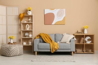 Oturma odasının içinde kanepeler, raflar ve vazolarda güzel nergisler var.