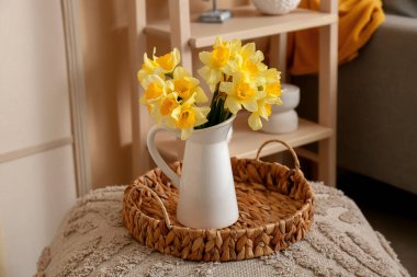 Üzerinde güzel sarı nergis buketi vazosu olan sepet tepsisi.