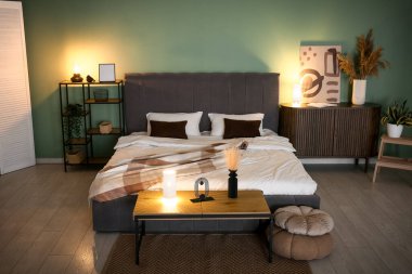 Yumuşak yataklı, ahşap çekmeceli ve geceleri parlayan lambalı bir yatak odası.