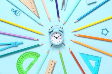 Alarm saatinden yapılmış çerçeve ve mavi arkaplanda okul kırtasiyesi