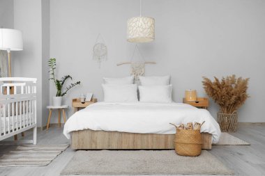 İçinde yatak, bebek yatağı ve masalar olan bir oda.