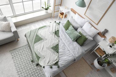 Konforlu yatağı, büyük penceresi ve çiçekleri olan aydınlık yatak odasının içi