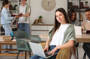 Kütüphanede dizüstü bilgisayarla çalışan kız öğrenci