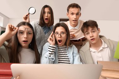 Kütüphanedeki masada dizüstü bilgisayarla çalışan öğrenciler şok oldular.