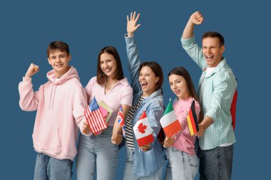 Mavi arka planda farklı bayrakları olan bir grup mutlu öğrenci.
