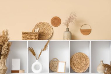 İçinde raf ünitesi ve vazolarda otlar olan bir oda.