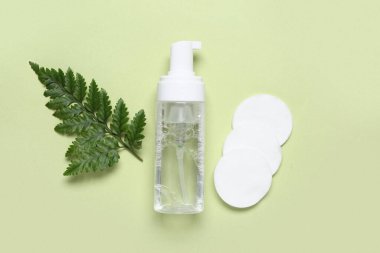 Bir şişe mikiler suyu, pamuk pedler ve yeşil arka planda yaprak.