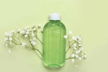 Bir şişe deniz suyu ve yeşil arka planda çiçekler.