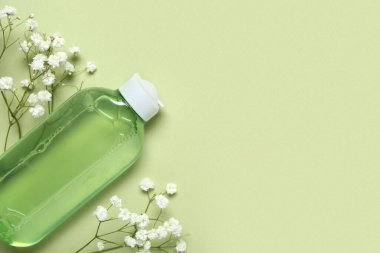 Bir şişe deniz suyu ve yeşil arka planda çiçekler.