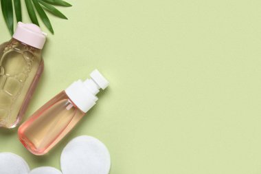 Su şişeleri, pamuk pedler ve yeşil arka planda yapraklar.