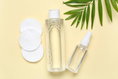 Micellar su, pamuk pedler ve bej arka planda yaprak