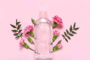 Bir şişe su ve pembe arka planda çiçekler.