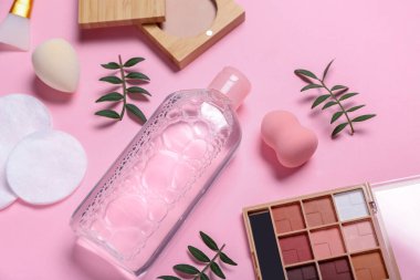 Pembe arka planda Micellar su, pamuk pedleri ve kozmetik ürünler