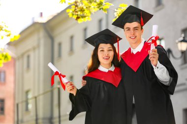 Mezuniyet gününde kucaklaşan diplomalı birkaç mutlu öğrenci.