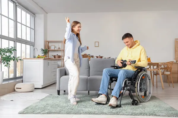 Tekerlekli sandalyedeki genç adam evde kız arkadaşı için gitar çalıyor.