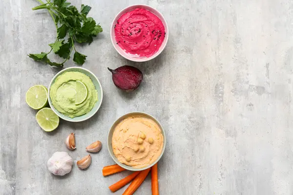 Maydanozlu, pancar ve havuçlu ve grunge arkaplanlı farklı lezzetli humuslar.