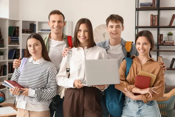 Kütüphanede dizüstü bilgisayarı ve kitapları olan bir grup öğrenci.