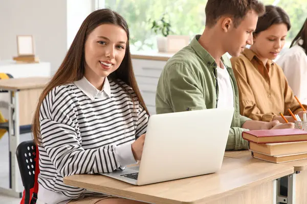 Dizüstü bilgisayarla çalışan kız öğrenci ve üniversitede sınıf arkadaşları.