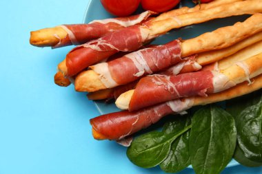 Lezzetli İtalyan Grissini tabağı, mavi arka planda pastırma, yakın plan.