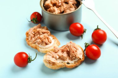 Lezzetli ton balıklı bruschettalar, teneke kutu ve domatesler mavi arka planda.