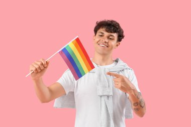 Pembe arka planda LGBT bayrağını gösteren genç adam