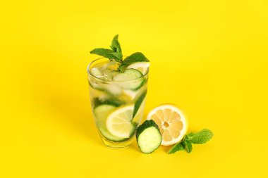 Bir bardak salatalıklı limonata ve sarı arka planda nane şekeri.
