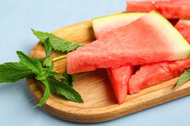 Mavi zemin üzerinde taze karpuz ve nane parçacıkları olan tahta.