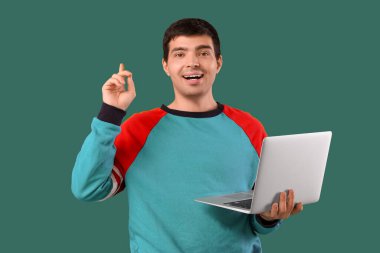 Yeşil arka plandaki bir şeyi gösteren dizüstü bilgisayarı olan erkek programcı