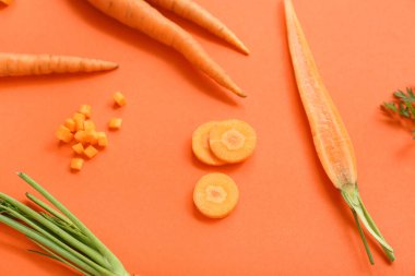 Turuncu arka planda taze havuç ve dilimler.