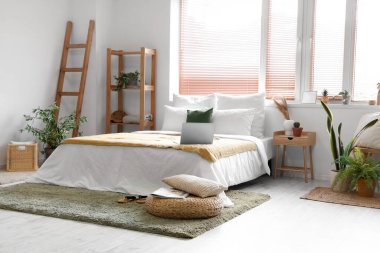 Şık yatak odasının içinde rattan puf var.