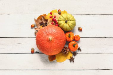 Olgun balkabaklarıyla, böğürtlenlerle, baharatlarla ve açık ahşap arka planda düşmüş yapraklarla sonbahar kompozisyonu