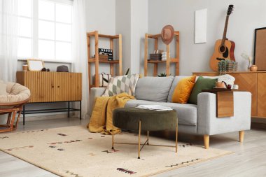 Gri kanepe, kanepe ve ahşap mobilyalarla modern oturma odasının içinde.