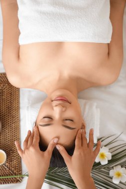 Genç Asyalı kadın spa salonunda baş masajı yaptırıyor.