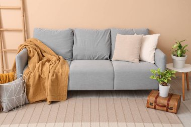 Battaniyeli gri kanepe ve bej duvarın yanındaki merdiven.