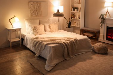 Rahat yatağın üzerinde yumuşak battaniyeler ve geceleri parlayan lambalar olan rahat yatak odasının içi.