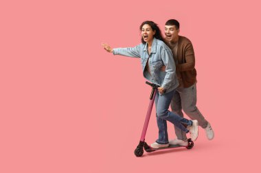 Pembe arka planda modern elektrikli scooter kullanan duygusal genç çift.