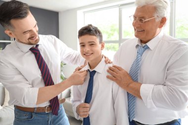 Babası ve büyükbabasıyla evde takım elbiseli genç bir çocuk.